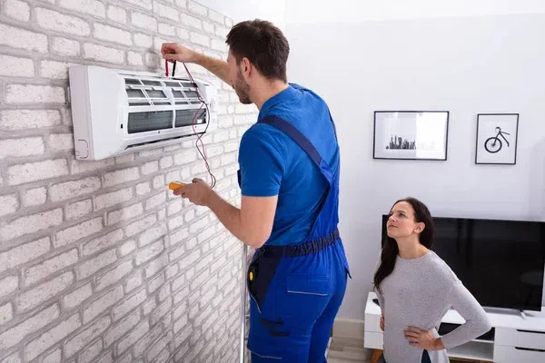 HVAC technician performing routine air conditioning maintenance and tune up service