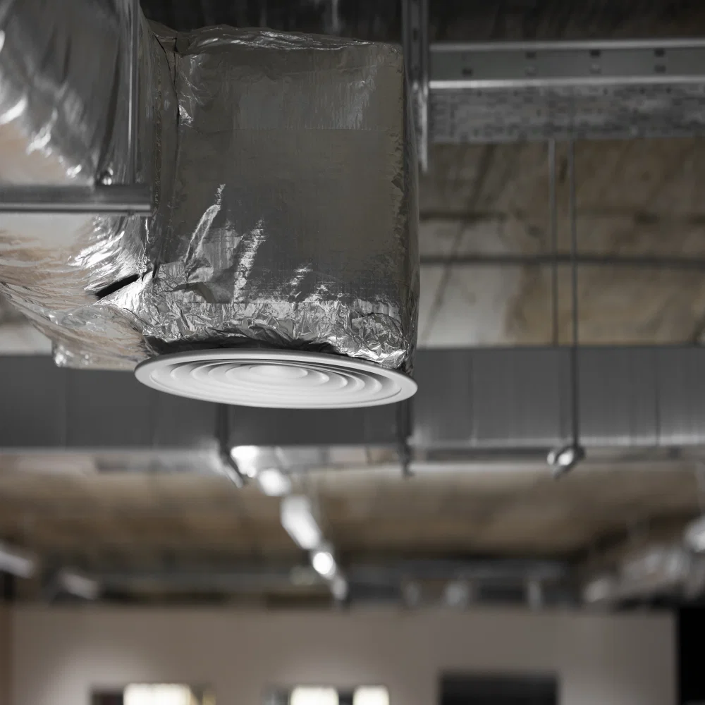 Experienced HVAC technician inspecting torn ductwork and testing airflow in attic