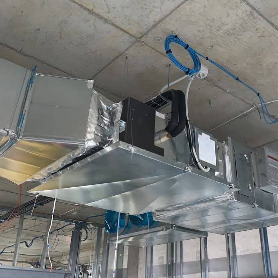 Technician fitting new duct runs above ceiling during Bay County home renovation